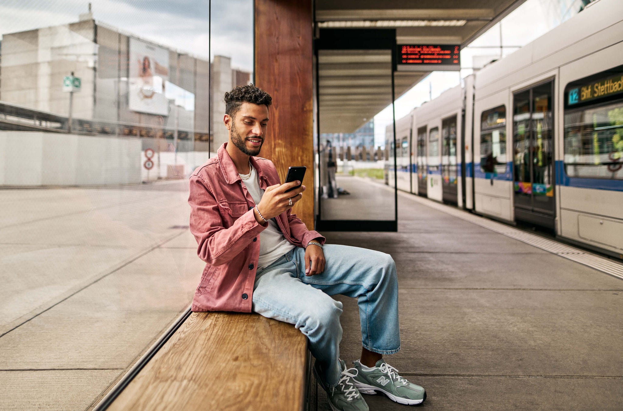 Abokauf mit wenigen Klicks in der ZVV-App Ein junger Mann an der Haltestelle erneuert in der ZVV-App sein Abo.
